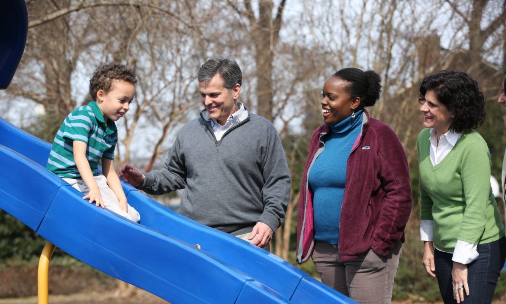 child sliding at playground while parent watch